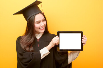 Beautiful woman in graduation gown is holding tablet mockup