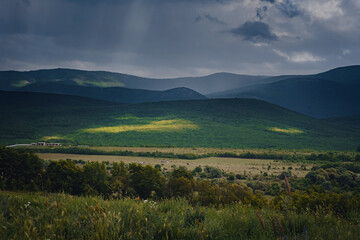 Picturesque green valley among the mountains before a storm.
