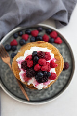 Stack of pancakes topped with yogurt and berries