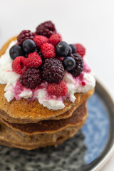 Stack of pancakes topped with yogurt and berries