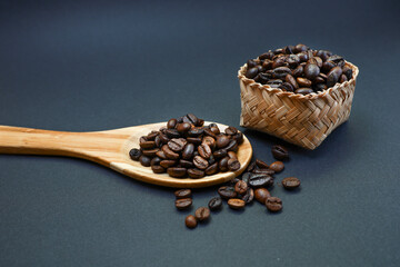 View from above of coffee beans in wooden spatula on black background