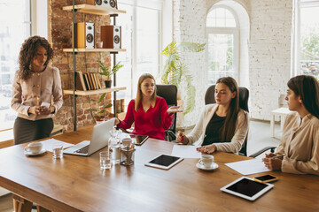Young caucasian business woman in modern office with team. Creative meeting, tasks giving. Women in...