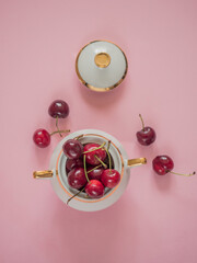 Cherries in white bowl on pink background