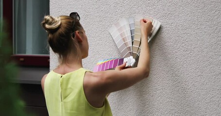 woman choosing paint color for house exterior stucco facade - Powered by Adobe