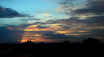Beautiful and dramatic sky with clouds over the city with a blurred view at Savar, Bangladesh. Blur Background with golden and reddish sunset abstract. Landscape beauty of City Sky.