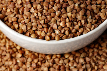 Bowl of raw uncooked buckwheat on wooden table