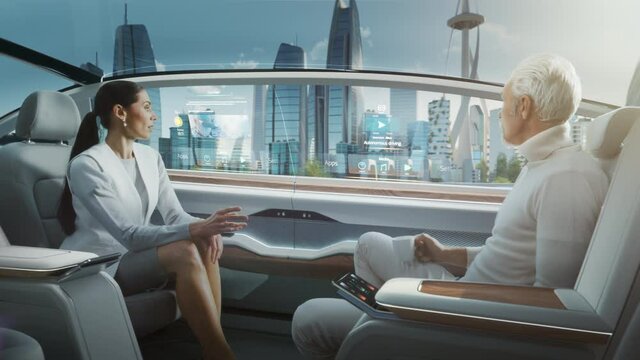 Beautiful Female and Senior Man are Having a Conversation in a Driverless Autonomous Vehicle. Futuristic Self-Driving Van is Moving on a Public Highway in a Modern City with Glass Skyscrapers.