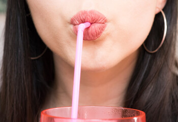 Close up of woman's lips drinking with a pink straw - obrazy, fototapety, plakaty