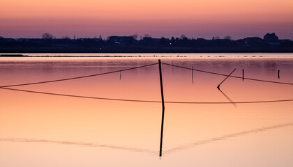 A series of landscapes of a salt lake in a seaside resort after sunset. Silhouettes in the pink sky and water. Pomorie resort, Bulgaria.