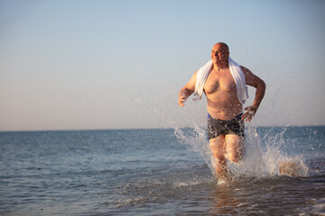 Fototapeta na wymiar An elderly man runs along the beach.