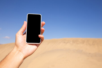 male hand with smartphone near sand hill in Maspalomas, Gran Canaria