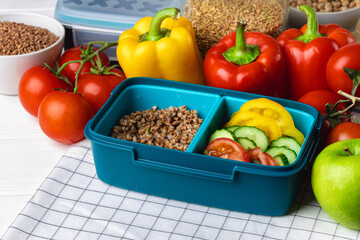 Lunch box with cooked buckwheat and fresh vegetable salad