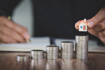 Woman hand hold a  home model put on the stack coin with growing, Savings money for buy house and...