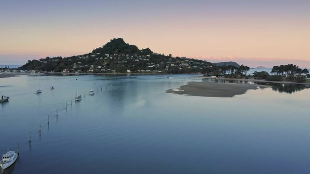 Aerial: Boats docked in the Tairua river at sunset. In the background is Mt Paku. Coromandel Peninsula, New Zealand