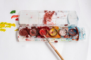 Watercolor paints and brush on a sheet of white paper © Vladimir