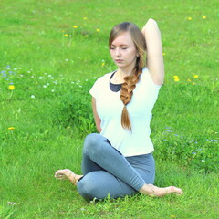 Young woman of European appearance does yoga in summer nature