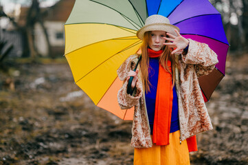 Funny and unusual girl in a long yellow skirt, white jacket and orange scarf rejoices