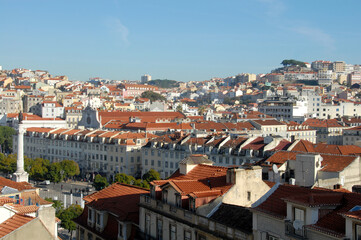 Fototapeta na wymiar Lisbon rises on the coast and is on a hilly area. From São Jorge Castle, the view is on the pastel-colored buildings of the old city, the Tagus Estuary and the 25 de Abril bridge.