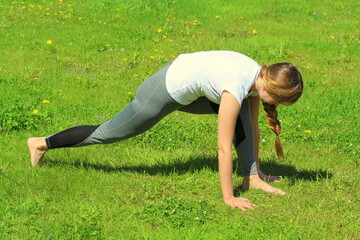 Fototapeta premium Young woman of European appearance does yoga in summer nature