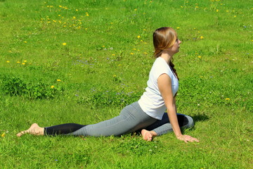 Young woman of European appearance does yoga in summer nature