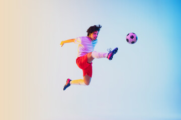 Fototapeta na wymiar Kicking in jump, on the run. Football or soccer player on gradient background in neon light - motion, action, activity. Concept of sport, competition, winning, action, motion, overcoming. Copyspace.