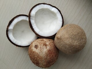  unhusked entire and broken coconut (Cocos nucifera) of Arecaceae family on a white background.