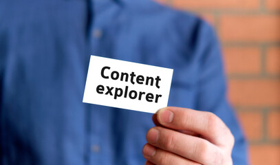 A man in a blue shirt holds a sign with the text of Content explorer in one hand