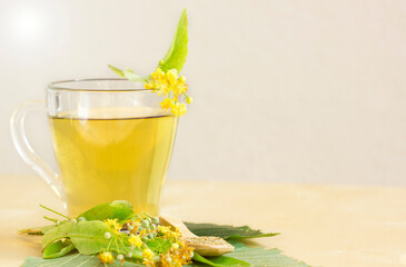 Cup of fresh herbal tea with blooming Tilia (linden, basswood) on light background. Side view. Close up. Space for text. herbal tea concept