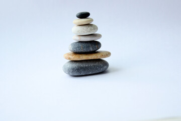 Smooth stones in the form of a pyramid on a light background. Zen concept. Horizontal photo. There is a place for text.
