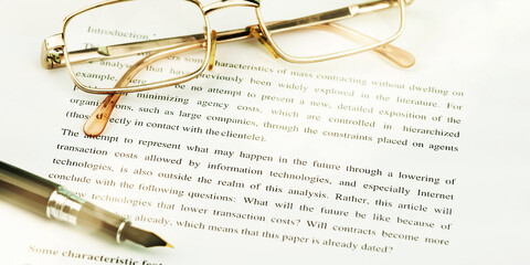golden glasses on white sheets of papers with black pen
