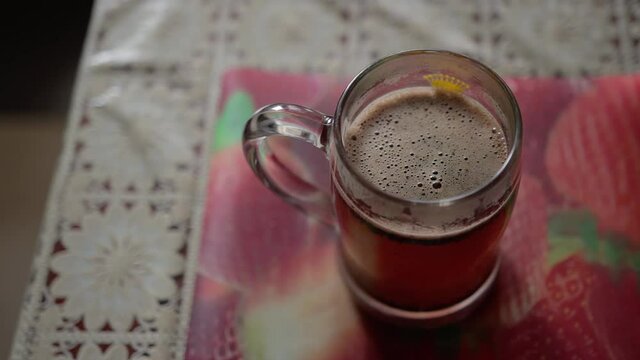 there is a coffee mug on the kitchen table. particles of ground grains settle to the bottom of the mug. steam rises over a mug of coffee