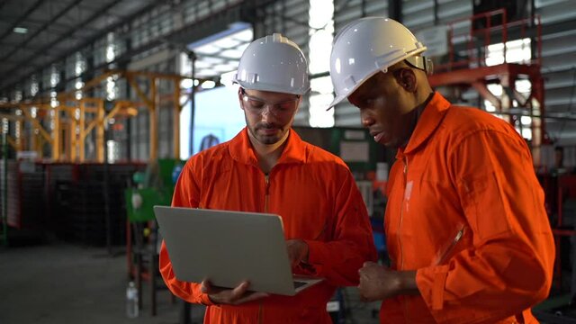 Two workers in production plant as team discussing, industrial scene in background