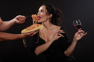 Beautiful girl eats spaghetti and drinks wine