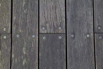 Fototapeta premium Top down view of wooden plank with texture, moss, cracks and nails on an outdoor walkway