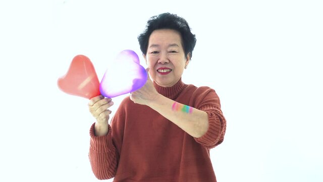 Asian elder mother support LGTBQ children thumb up smile with rainbow pride paint purple red balloon heart