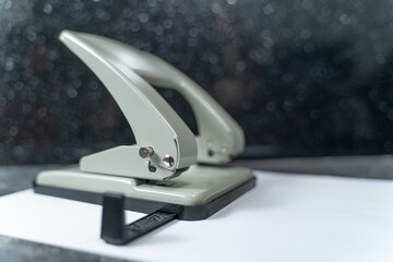 hole punch lying on a white sheet of paper on a gray marble table