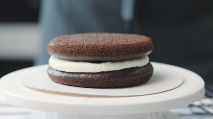Cooking cake at home. Two levels on chocolate cake with white cream and cherry jam in between