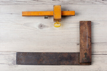 Antique set square and mortise gauge isolated on a light wooden background