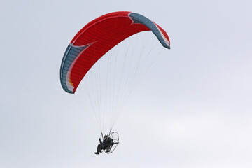 Paramotor pilot flying in a blue sky