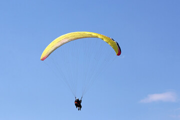 Tandem Paraglider flying wing in a blue sky	