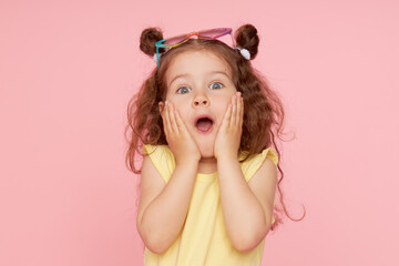 Portrait of a happy child. Cute little girl with a funny face on a pink background. Advertising...