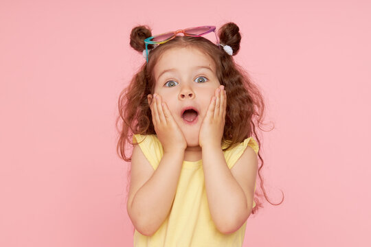 Portrait of a happy child. Cute little girl with a funny face on a pink background. Advertising baby products