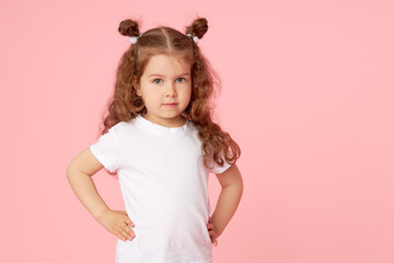 Portrait of cute european little toddler girl over pink background. Looking at camera. Child model in white T-shirt. Advertising childrens products