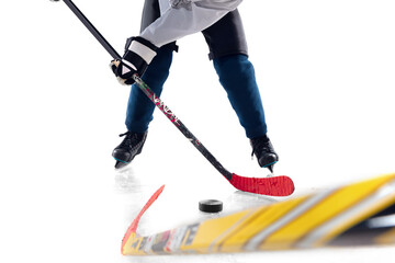 Obraz premium Unrecognizable male hockey player with the stick on ice court and white background. Sportsman wearing equipment and helmet practicing. Concept of sport, healthy lifestyle, motion, action. Close up.
