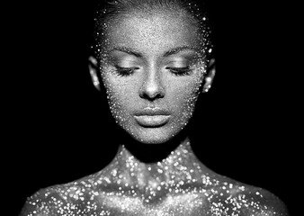 Fashion model woman in bright sparkles and lights posing in studio. Portrait of beautiful sexy woman. Art design glitter glowing make up. Black and white photography