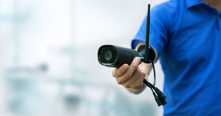 security cameras and cctv services background - man holding ip camera in hand with copy space