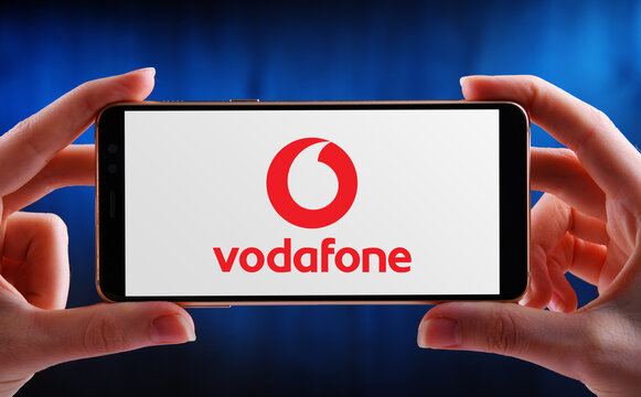 Hands holding smartphone displaying logo of Vodafone