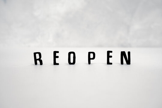 Black Letters Read REOPEN Set Against A Plain White Surface And Light Grey Background.  Concept Image Of Businesses Reopening After Corona Virus Lockdown