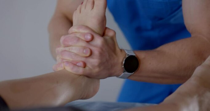foot massage by chiropractor in modern osteopathic clinic, masseur is massaging female feet