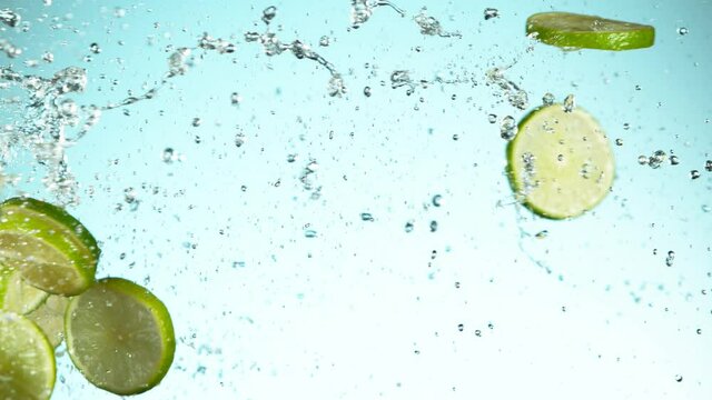 Super slow motion of lime pieces collision with water splashes, white background. Filmed on high speed cinema camera, 1000 fps.